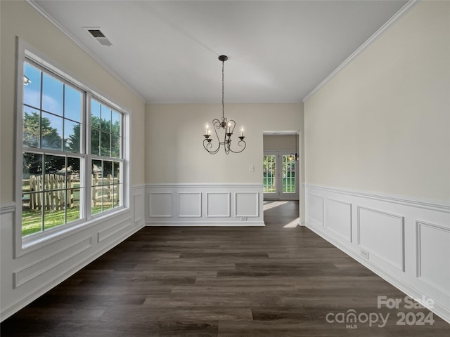 unfurnished dining area with visible vents, wainscoting, an inviting chandelier, dark wood finished floors, and crown molding