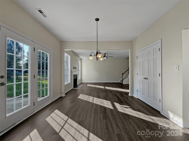 unfurnished dining area featuring baseboards, visible vents, dark wood-style flooring, an inviting chandelier, and stairs