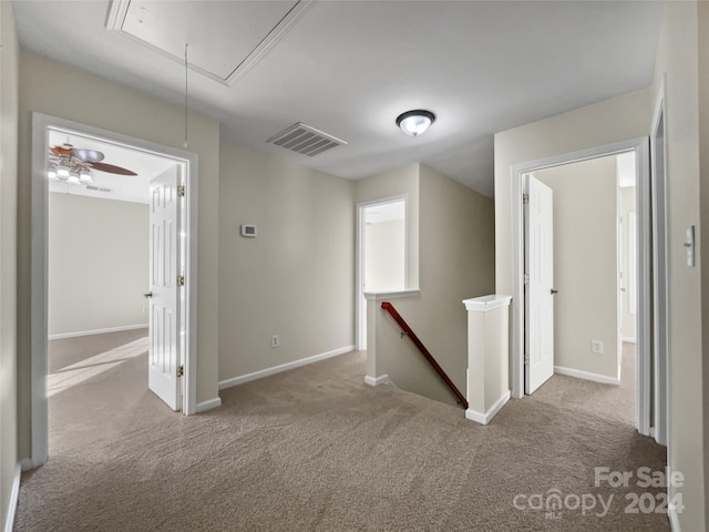 hall featuring light colored carpet, visible vents, baseboards, an upstairs landing, and attic access