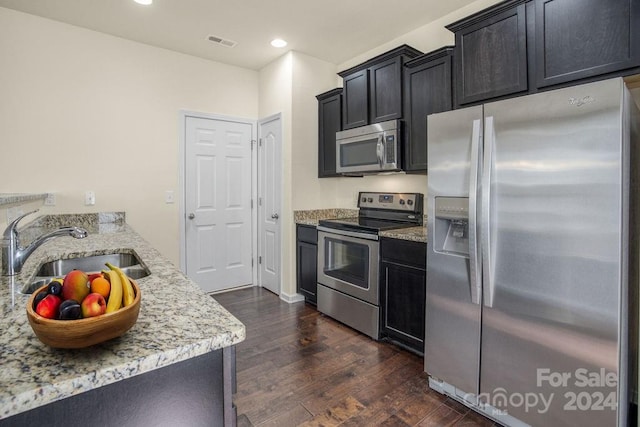 kitchen featuring sink, light stone countertops, appliances with stainless steel finishes, and dark hardwood / wood-style flooring