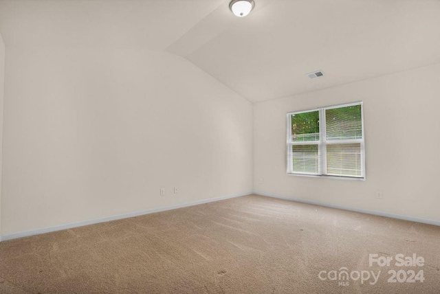 carpeted spare room with lofted ceiling