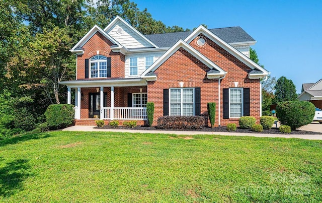 view of front of property featuring a front yard, covered porch, and brick siding