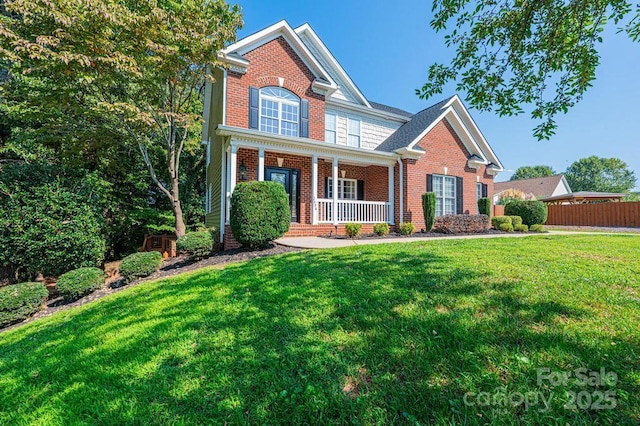 traditional home with brick siding, a front lawn, a porch, and fence