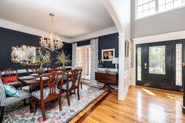 dining room with arched walkways, a chandelier, wood finished floors, and crown molding