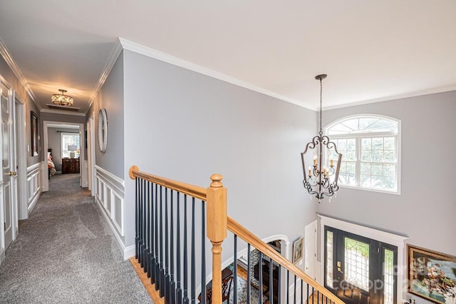 corridor with a healthy amount of sunlight, carpet, a notable chandelier, and an upstairs landing