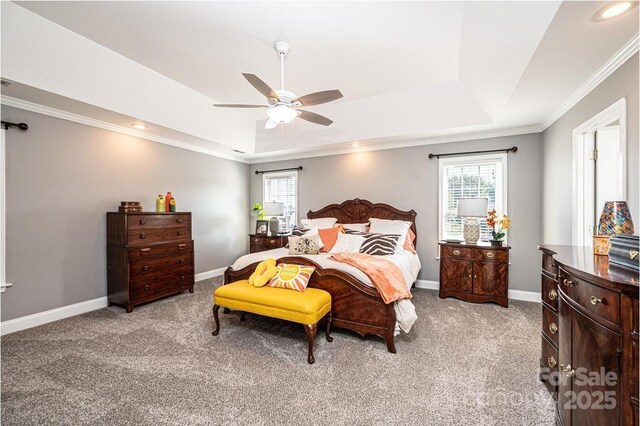 bedroom featuring light carpet, baseboards, multiple windows, and a tray ceiling