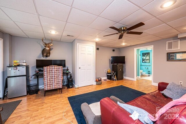 living area with a paneled ceiling, wood finished floors, visible vents, and baseboards