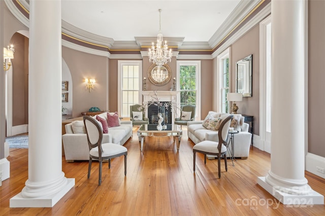 living room with a high end fireplace, decorative columns, and light hardwood / wood-style floors