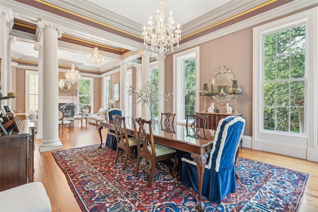 dining space with ornamental molding, an inviting chandelier, decorative columns, and light hardwood / wood-style floors