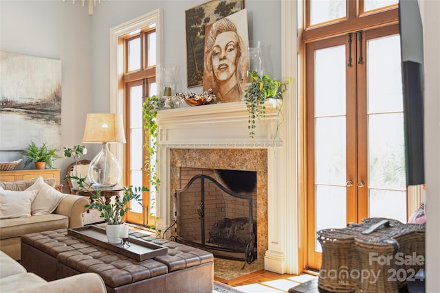 living room with french doors, a premium fireplace, and wood-type flooring