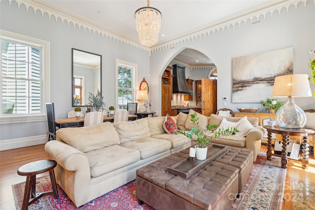 living room with ornamental molding, wood-type flooring, and a chandelier