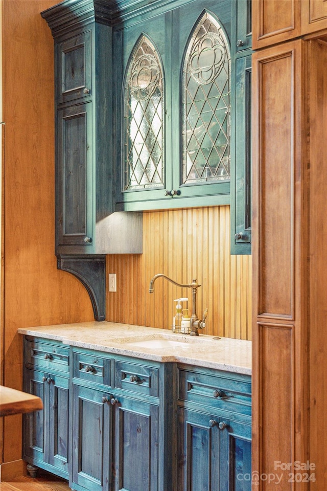 kitchen with wood walls, light stone counters, and sink