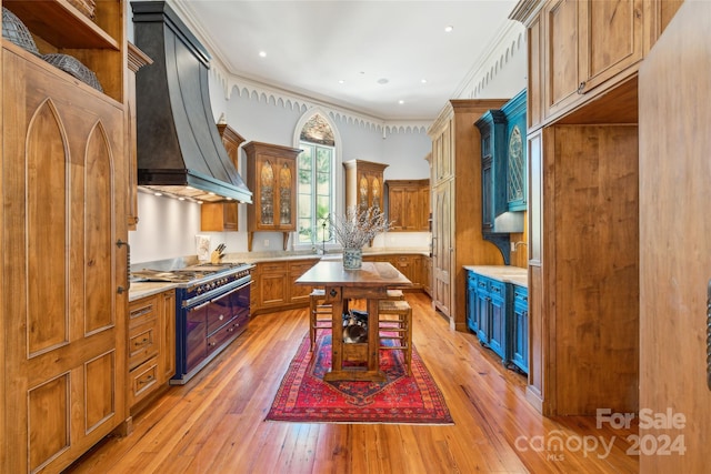 kitchen with light hardwood / wood-style flooring, crown molding, custom range hood, and double oven range