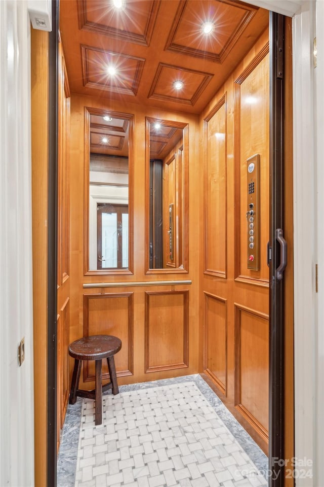 room details featuring coffered ceiling, elevator, and wooden walls