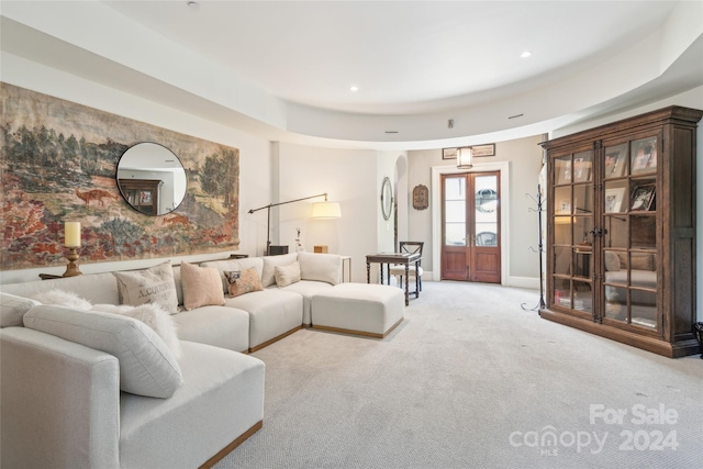 carpeted living room featuring a raised ceiling and french doors