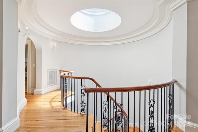 hallway with a tray ceiling and light hardwood / wood-style floors