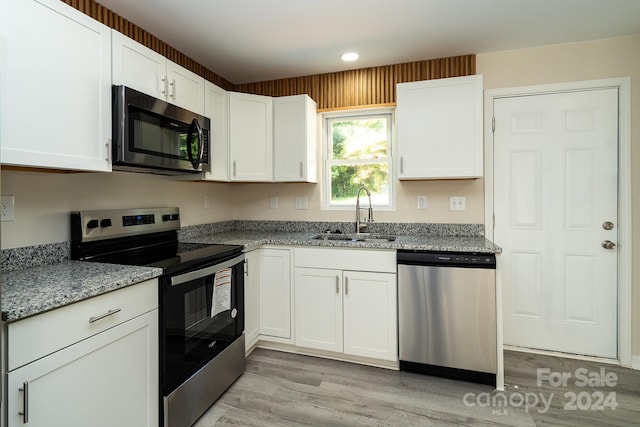 kitchen featuring sink, light wood-type flooring, light stone counters, white cabinetry, and stainless steel appliances