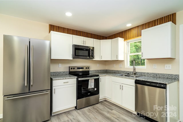 kitchen with stainless steel appliances, light hardwood / wood-style floors, white cabinetry, sink, and light stone countertops