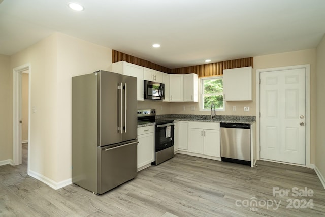 kitchen with sink, stainless steel appliances, white cabinets, and light wood-type flooring