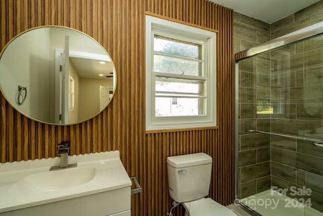 bathroom with a shower with shower door, toilet, and a healthy amount of sunlight