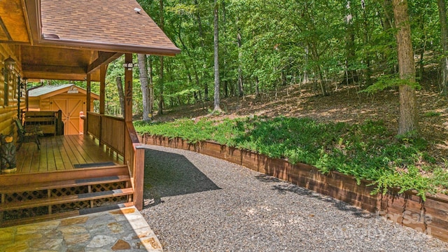 view of yard featuring a deck, an outdoor structure, and a view of trees