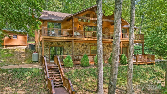 exterior space featuring log veneer siding, stone siding, a shingled roof, and a wooden deck