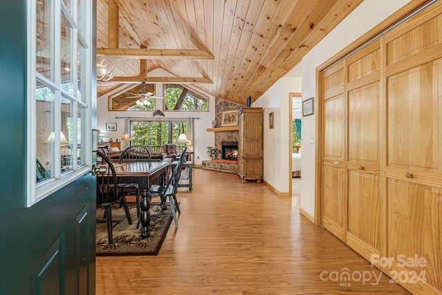 dining room with wood ceiling, light wood-type flooring, lofted ceiling with beams, a fireplace, and a ceiling fan