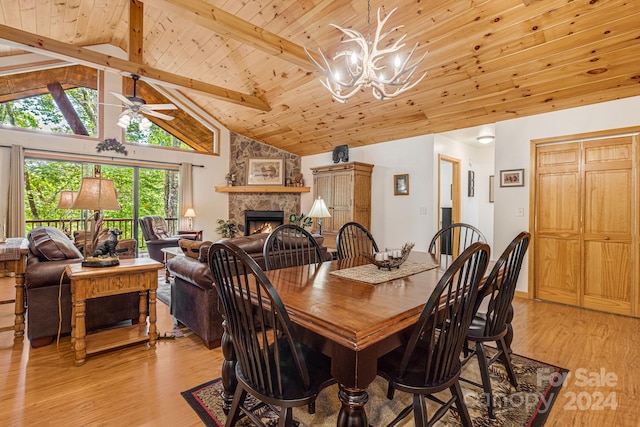 dining area with a stone fireplace, beamed ceiling, wood ceiling, and light wood-style floors