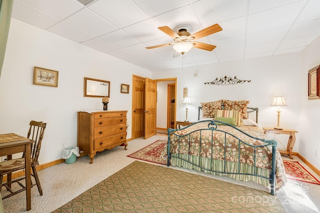 bedroom featuring a drop ceiling, baseboards, carpet, and ceiling fan