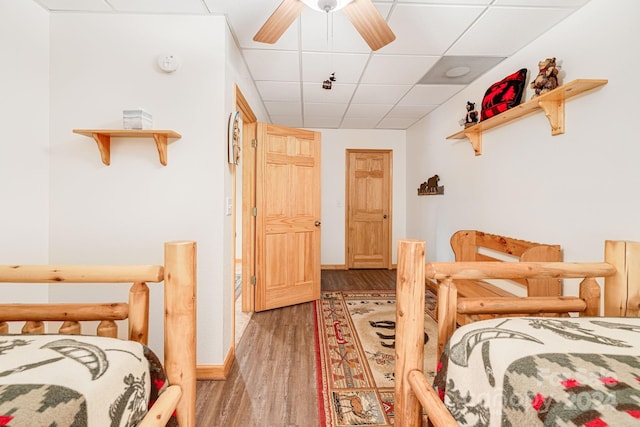 bedroom featuring a drop ceiling, ceiling fan, and light wood-style floors