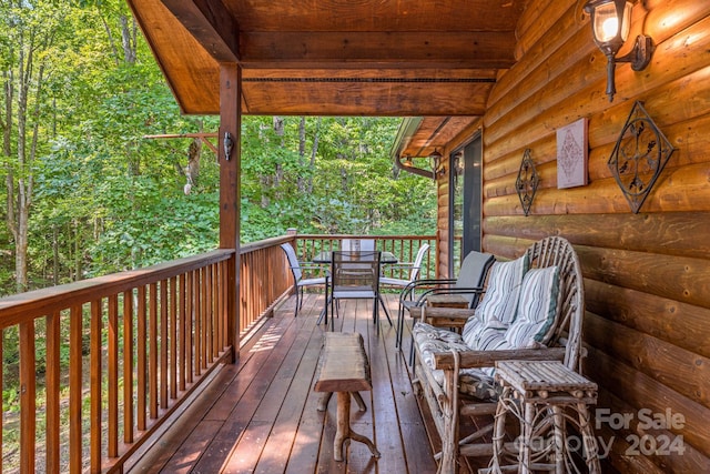 wooden terrace featuring a forest view and outdoor dining area