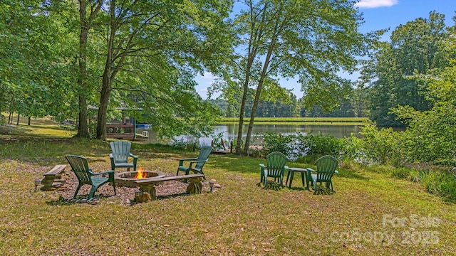 view of green lawn featuring an outdoor fire pit and a water view