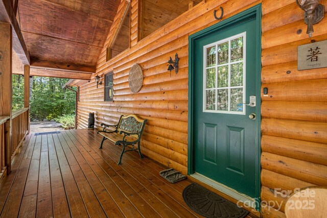 property entrance with log veneer siding and a porch