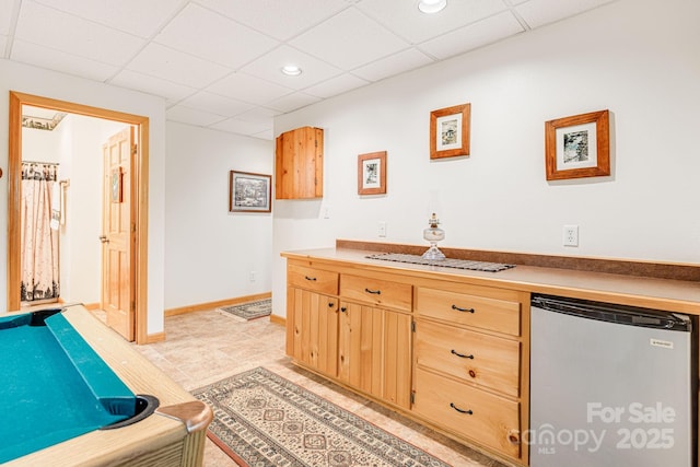 bar area featuring refrigerator, a drop ceiling, recessed lighting, and baseboards