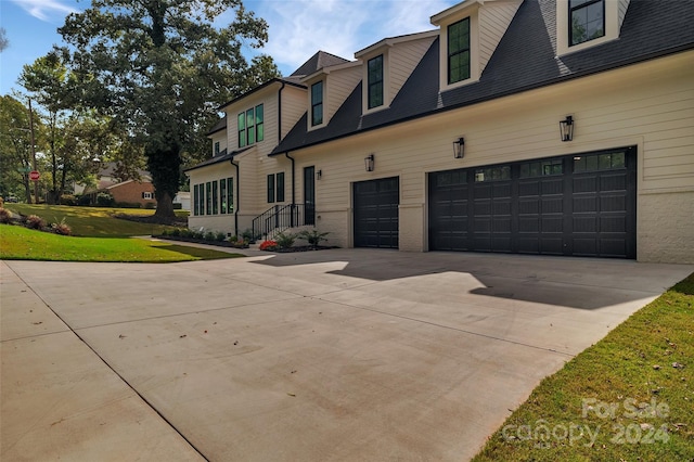 cape cod-style house featuring a garage and a front lawn