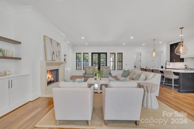 living room featuring light wood-type flooring, sink, and crown molding