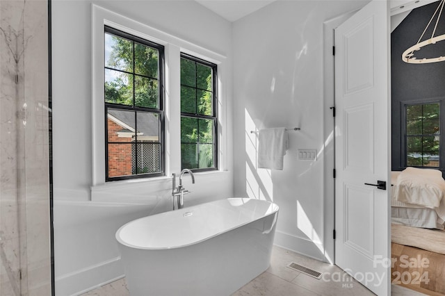 bathroom with a tub to relax in and tile patterned floors