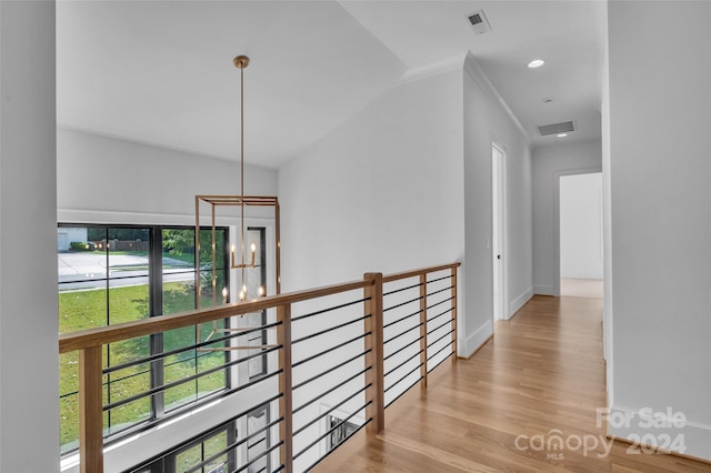 hall featuring an inviting chandelier, light wood-type flooring, plenty of natural light, and crown molding