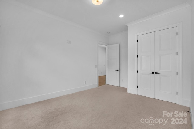 unfurnished bedroom featuring carpet flooring, ornamental molding, and a closet