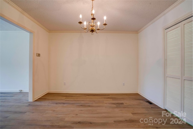 empty room featuring hardwood / wood-style flooring, a chandelier, crown molding, and a textured ceiling