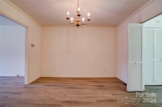 unfurnished dining area with hardwood / wood-style floors, crown molding, a notable chandelier, and a textured ceiling