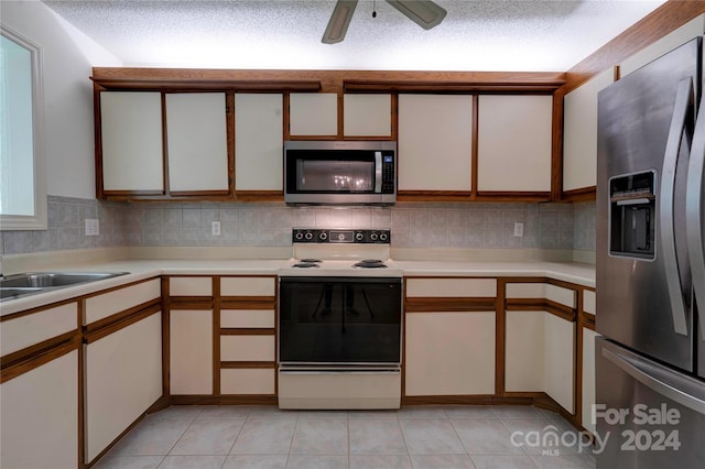 kitchen with light tile patterned floors, stainless steel appliances, white cabinetry, and a textured ceiling