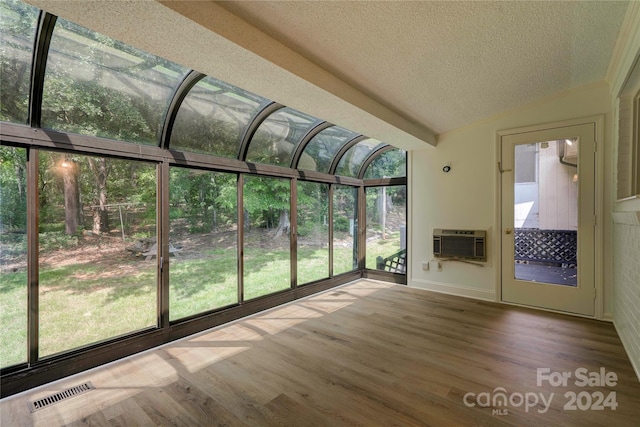 unfurnished sunroom with lofted ceiling, a healthy amount of sunlight, and an AC wall unit