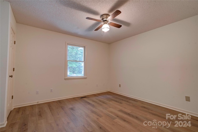 empty room with a textured ceiling, light hardwood / wood-style flooring, and ceiling fan