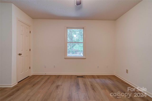 spare room featuring ceiling fan, light hardwood / wood-style floors, and a textured ceiling