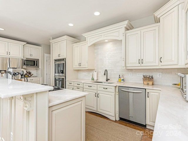 kitchen featuring built in appliances, a center island, sink, decorative backsplash, and hardwood / wood-style flooring