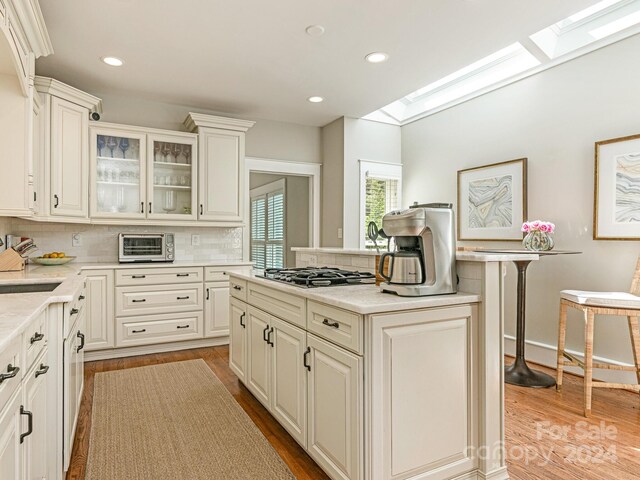 kitchen with light hardwood / wood-style flooring, backsplash, and a skylight