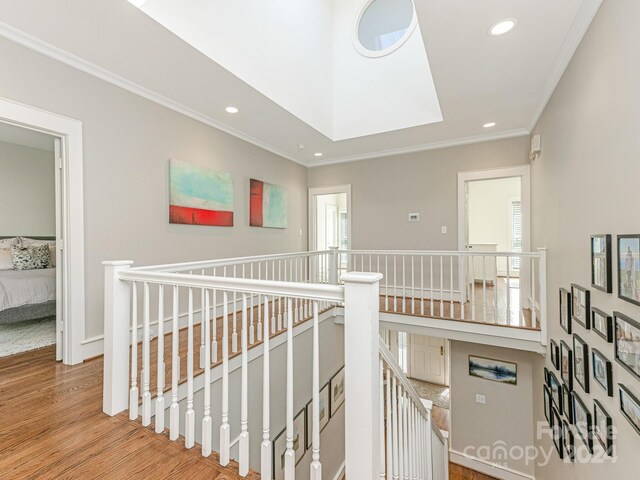 hall with crown molding, light hardwood / wood-style flooring, plenty of natural light, and a skylight