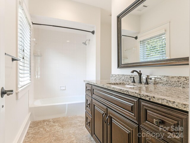 bathroom featuring tiled shower / bath, vanity, and tile patterned flooring