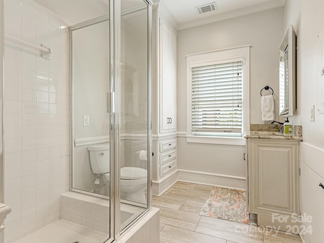 bathroom featuring tile patterned flooring, a shower with door, crown molding, toilet, and vanity